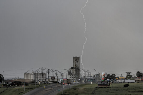 A lightening bolt cuts through the steel gray sky behind a grain elevator, a symbol of high plains rural America, that has lost more than 12 million people since 2000. Just 16 percent of the nation’s population lives in rural areas – the lowest in recorded history and down from 72 percent a century ago. 
Dodge City, Kansas like all towns on the high plains, have been seriously diminished by the rush to the cities. After the Dust Bowl and the family farm crisis and the domination of BIG AG that requires fewer people to produce more crops, communities face another crisis. With a dwindling supply of water, farmers unable to fill their grain elevators threatens communities further and grain will come in on the rails from other areas. Even with the water they have now, small, dusty towns are getting smaller and dustier.
 
