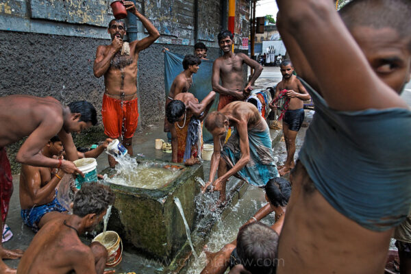 Large group of untouchables bathing in former British horse watering trough in Calcutta, Bengal State, India.
Crowds on the streets of Calcutta gather around these corner water fountains that were put in place by the colonizing British to water their horses. Now, with so many people in Calcutta, it has become a mass bathing area. The rapid growth of cities like Chicago in the late nineteenth century and Calcutta a century later can be attributed largely to rural-urban migration. This kind of growth is especially commonplace in developing countries. The urbanization of the world’s population over the twentieth century has been dramatic—13% of the population lived in cities in 1900, 29% in 1950, 49% in 2005, and likely 60% (4.9 billion) by 2030. According to the UN State of the World Population 2007 report, sometime in the middle of 2007, the majority of people worldwide will be living in towns or cities for the first time in history; this is referred to as the arrival of the “Urban Millennium” or the ‘tipping point.’ In regard to future trends, it is estimated that 93% of urban growth will occur in developing nations—80% of it occurring in Asia and Africa.
