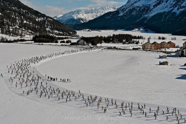 The Engadin Ski Marathon attracts 16,000 cross-country skiers who race from the far end of Lake Maloja skiing across the frozen ice to St. Moritz, Switzerland. First held in 1969, the 42 km long marathon leads athletes beside a Medieval castle, ice bound lakes and through an entire forest. This aerial photograph shows the stunning alpine scenery beyond the skiers dotting the course near the start of the competition.
