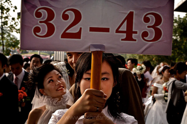 Brides numbered 32 through 43 line up in their queue at the Rose Wedding Festival. Seventy couples in this mass marriage ceremony started at a shopping mall, then traveled to Century Park for the ceremony. The marriage-age consumer is a prime target for first-world companies. The middle class’s under-30-consumer market alone will be the size of the entire EU market in the next decade.
