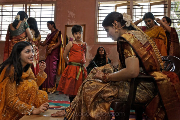 India Wedding | Bride in Half Million Dollar Outfit
Wearing her fortune, from gold threads in her sari to a priceless heirloom headpiece, Nagavi sits with family on her wedding day in India. Gold trappings advertise the value she’ll bring to the union.
