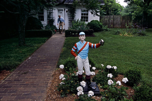 The Bluegrass Region is rich with lore and traditions like the lawn jockey, a small statue prominently positioned on every farm with a lantern or hitching ring in one outstretched hand. Local legend says it memorializes Jocko Graves, who stood guard over horses for George Washington and froze to death holding a lantern in his hand. He was known as the faithful guardsman.
Modern day watchman and farm owner Dr. Smiser West walks out his office door toward the lawn jockey painted with the colors of Waterford Farm.
