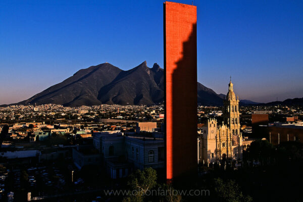 The most recognized symbol of Monterrey, Mexico is Cerro de la Silla, the saddle-backed mountain range. It is the backdrop behind the modern orange sculptural monument with laser beams, “Faro Del Comercio” or “Beacon of Commerce,” by sculpture Luis Barraz which contrasts Baroque style Cathedral of Monterrey, the traditional cathedral. Beyond the Macro Plaza, both colonial and contemporary architecture are found on the streets. The third largest city in Mexico, Monterrey is the capital of Nuevo Leon. It is an industrial and commercial city with cultural interests. It’s said that Monterrey faces more to the north and the United States than South to Latin America.
 
 
