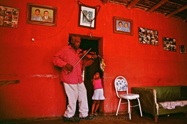 Amador Ballumbrosio, learned to play Afro-Peruvian music from his grandfather when he was four years old.  He taught his children and grandchildren the music he first learned which was like the blues, he says. But the popular dance of the community is now more upbeat. His grand daughter watches as he plays in the living room of his home. The community of El Carmen is made up of slave descendants from Africa, well known for their Afro-Peruvian music and dance.
