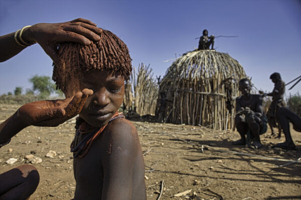 A child in the Ethiopian Hamar village of Logira gets her hair done before a wedding. A tradition in the Omo River Valley, the Hamar have a distinctive hairstyle that involves curling the hair with a mixture of butter and ochre clay.
