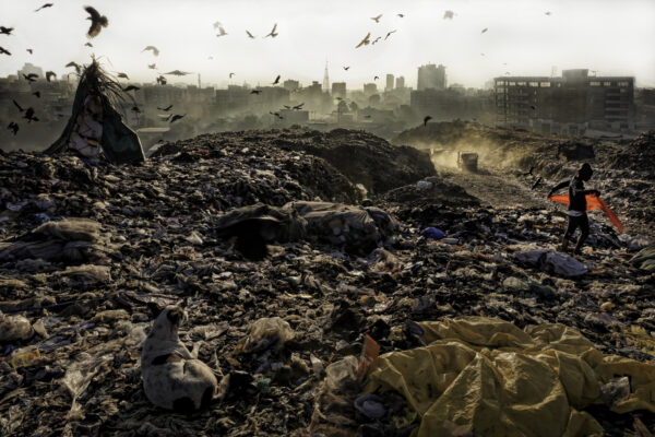 



A plastic worker walks from her tent and begins her morning by finding a discarded piece of red material to add to her outfit. A dog watches her and birds fly over this city of garbage which is the Kalyan Dumping Ground in Thane district outside Mumbai. Most all the trash pickers were gathering plastic, a precious find for recycling.




