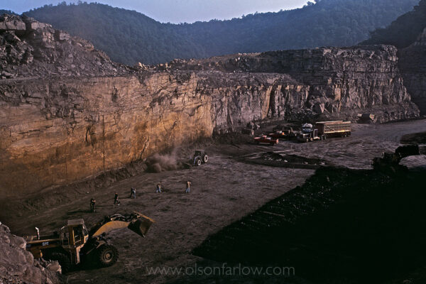 Bulldozers fill trucks with excess rock at a small mountaintop removal site in Man, West Virginia, where a small crew is mining coal in a site in Logan County that was left by a large coal company as rubble.
Large mining operations are only visible from the air, although coal and debris are removed using enormous earth-moving machines known as draglines that stand 22 stories tall and can hold 24 compact cars in its bucket. The machines can cost up to $100 million, but are favored by coal companies because they can do the work of hundreds of employees. A small operation like this one can keep 17 employees working for five years and making good wages.

