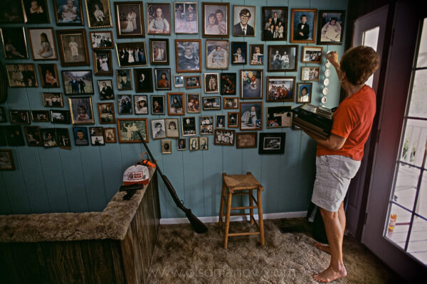Lorene Caudill prepares for their move by taking down family photographs. She and her husband Therman endured eight years of coal dust and foundation-shaking dynamite blasts as Hobet 21, one of the largest surface mines in the state, inched slowly toward them. They put up apples from their last garden and packed their belongings after signing a letter of intent to sell their beloved home to Arch Coal Company (now Patriot Coal).
The Caudills, along with other family members, did achieve a small victory by preserving ownership of a nearby ancestral home but only after a long battle—all the way to the West Virginia Supreme Court—with the coal company.  No one lives there now but the extended family gathers on weekends to garden and for dinners at the house, which was completely surrounded by mining. Since then, the house was burned down by arsonists.
The Caudill house, where they had planned on spending the rest of their lives, is a half-mile down the road from the old homestead. They are some of the last to leave the community. Therman Caudill, a retired schoolteacher said, “It took the coal company 125 years to run the Caudill family out of Mud River, but they finally did it.”
