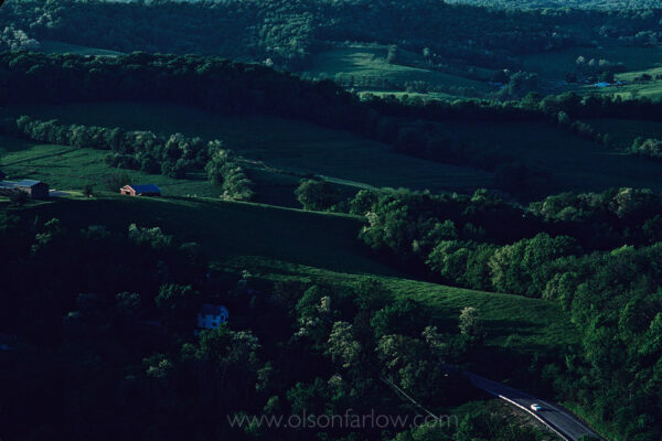 


A car passes through the hilly terrain of a rural section of the National Road in Western Pennsylvania. The aerial shows farm land a few miles east of Scenery Hill.
Construction began in Cumberland, MD in 1811 on the National Road, America’s first highway built with federal funds. Reaching Wheeling, West Virginia in 1818, it ended more than 600 miles west in Vandalia, Illinois in 1852. What began as a wagon train road to settle the West is now Main Street to many towns. Communities sprang up through Ohio, Indiana and IL during the beginning of a prosperous automobile era.



