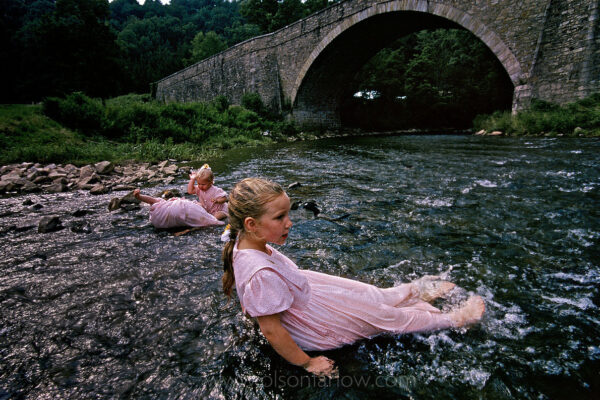 Sunday church dresses double as bathing suits for the young sisters below the Casselman River Bridge near Grantsville, Maryland. Now closed to all but foot traffic, the bridge was built in 1811. The 50-foot arch, like a lone cathedral rib, was designed to clear a canal that never came.
