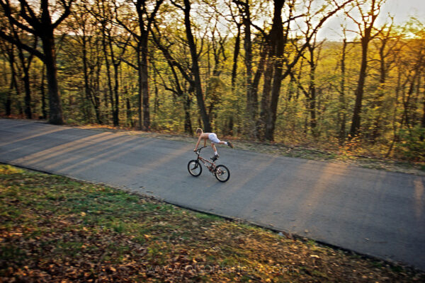 A young daredevil bicyclist rides down a carriage road that is closed to vehicular traffic in Iroquois Park. Frederick Law Olmsted created a network of pedestrian pathways and curving roads for carriages, but might not have ever imagined this use.
Iroquois Park is known for its panoramic views and long winding roads to the top of 725-acre park in Louisville, Kentucky.  Three parks Olmstead planned in Louisville are named to honor a Native American Indian tribe—Cherokee, Shawnee and Iroquois—that once shared the dark and bloody hunting grounds of Old Kentucky.
