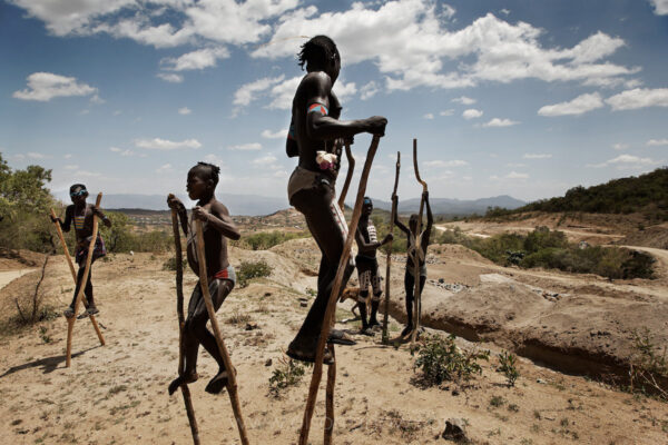 There are only dirt roads through this region of the Omo River Valley, but a paved highway is being built.  Children with body paint practice walking with hand-made stilts hoping for a few pennies from tourists riding in cars the roads will bring through Ethiopia.
