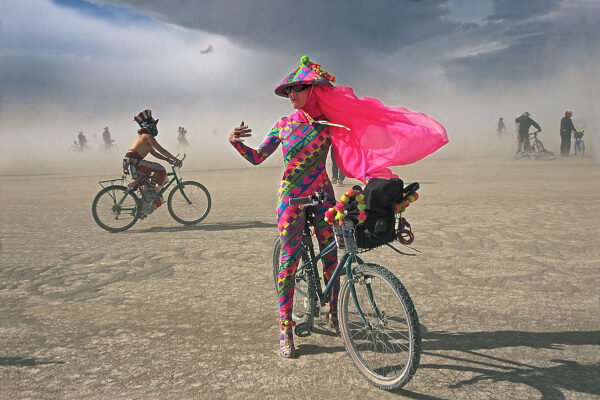 A wildflower blooms in the dry lakebed of the Black Rock Playa Desert as California costume designer Jeanne Lauren braves a sandstorm at Burning Man festival in northwestern Nevada’s National Conservation Area.
Visibility is diminished as harsh winds blow up a sands over the performance artists. Over 50,000 people create an instant city that celebrates art in a unique counter-culture experience. Beyond Uncle Sam’s wheels is the vast salt flat or dry lakebed, and one of Earth’s flattest spots.
