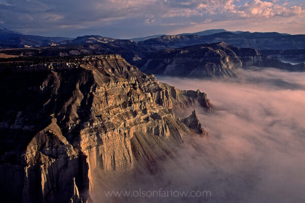 Morning fog fills a canyon below sheer sandstone cliffs of Grand Staircase Escalante National Monument in Utah. The rugged and unique terrain of arches, plateaus, multi-colored cliffs, plateaus, mesas, buttes, pinnacles, and colorful canyon walls covers 1.7 million acres. The highest point is the Kaiparowits Plateau, an 800,000-acre region that forms the wildest, most arid, and most remote part of the Monument.
Grand Staircase is the largest of the 13 National Monuments that were designated by President Bill Clinton and Department of the Interior Secretary Bruce Babbitt.
 
