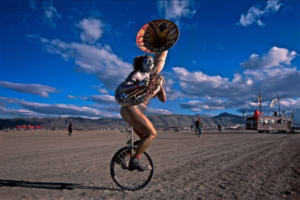 Wearing a smile and a sousaphone, “Red” makes music in a balancing act during the annual Burning Man art festival in Nevada’s Black Rock Playa (dry lake). The silver-painted Thompson was like a fleeting mirage, spinning by on her unicycle before disappearing into the crowd.
Costumes and performance art, sculptures and unique vehicles abound during a week full of whimsy and humor.
“There are no spectators,” says Red, “only participants.” The counter-culture celebration held annually in the Nevada desert attracts 50,000 people.
