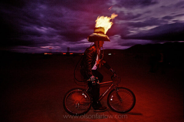 A man with a hat of flame rides a bicycle at the Burning Man Festival. Elaborate, colorful, and clever costumes are part of the annual, weeklong festival held in Black Rock Desert in northwestern Nevada’s Conservation Area. The counter-culture celebration focuses on art and self-expression.
