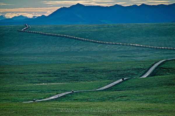 A thin ribbon of humanity flows across the tundra along Alaska’s Dalton Highway. Nearby, the trans-Alaska pipeline carries Prudhoe Bay oil south 800 miles to the port of Valdez. The Dalton highway and the Alaska pipeline ae visible in the open tundra of the North Slope.
The road was built for the pipeline and is known as the “haul road” for the trucks carrying supplies as the pipeline was built. It was named after James William Dalton, an Arctic engineer involved in early oil exploration efforts. The Trans-Alaska pipeline, which runs through Bureau of Land Management land above the Yukon River and Brooks Range, originally cost $8 billion and was completed in the 1970s.
The Dalton highway ends 414 miles north of Fairbanks in Deadhorse, the farthest north you can drive in Alaska. Support pipes along the Alaska Pipeline are cooled by refrigerant coils that keep them from transmitting heat into the thaw-sensitive permafrost. The pipeline pumps 47,000 gallons of oil a month. The Bureau of Land Management oversees 2.1 billion acres of land along the Dalton Highway north of the Yukon River.
