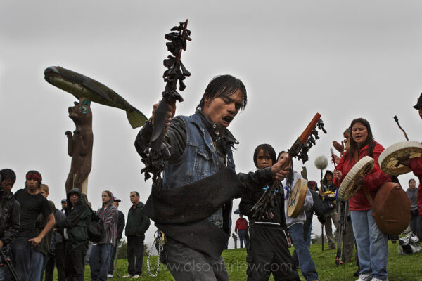 Rain didn’t dampen the spirits of native Tlingets who danced and sang following a historic totem raising ceremony where seven poles were added to the Tlinget park in Klowock on Prince of Wales Island. People carried a pole through the town where it was carved and all helped pull on ropes to raise it into place. Tlingit, Haida, and Shimshane people came together for the historic event in southeast Alaska.
The meanings of the designs on totem poles are as varied as the cultures that make them, but totem poles were never objects of worship. Carvings may recount familiar legends, clan lineages, or notable events. Some poles celebrate cultural beliefs, but others are mostly artistic presentations. Certain types of totem poles are part of mortuary structures, and incorporate grave boxes with carved supporting poles, or recessed backs for grave boxes. Poles illustrate stories that commemorate historic persons, represent shamanic powers, or provide objects of public ridicule.
