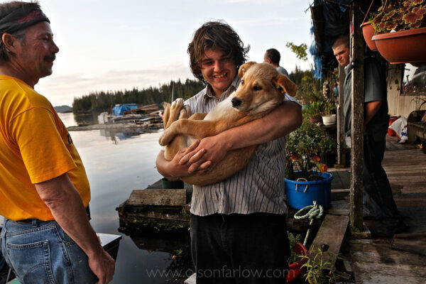 Holding his puppy, “Meatball,” a youth hangs out on the dock of the float house where he lives with Swede and Shirley. The family built a float house off the coast of Prince of Wales Island which is only accessible by float plane or by boat. The houses are characteristic of southeast Alaska, and are tied down with ropes and floating on the water in isolated bays.
Life in remote Alaska offers adventures and an atypical lifestyle rich in experiences.
